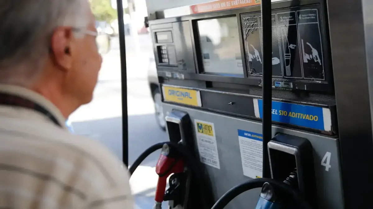Cliente diante de bomba de diesel em posto de combustível, ilustrando o reajuste do ICMS dos combustíveis