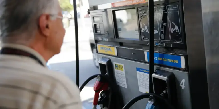 Cliente diante de bomba de diesel em posto de combustível, ilustrando o reajuste do ICMS dos combustíveis