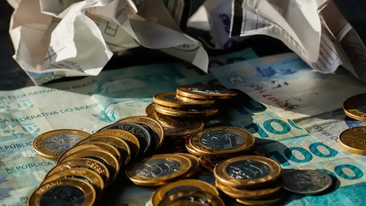 Moedas e cédulas de real sobre a mesa, ilustrando a alta do dólar e a queda do Ibovespa após a eleição