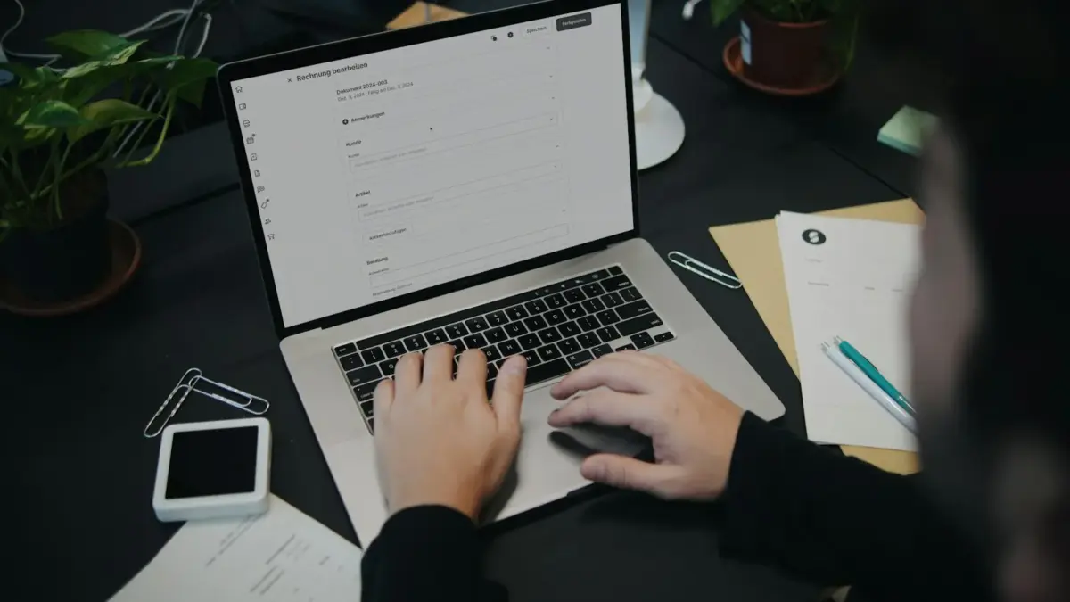 Pessoa digita em notebook com tela de edição de nota de serviço, ilustrando a NFS-e nacional no Simples