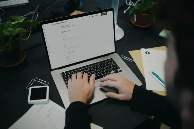 Pessoa digita em notebook com tela de edição de nota de serviço, ilustrando a NFS-e nacional no Simples