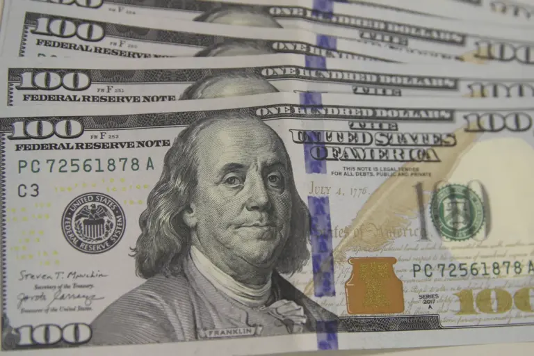Notas de cem dólares enfileiradas, ilustração da alta de 9,15% do dólar na semana até 30 de outubro de 2026