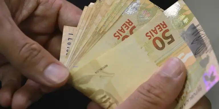 Mãos contam notas de R$ 50, ilustrando as estatísticas de pagamentos de varejo do Banco Central no primeiro semestre de 2026